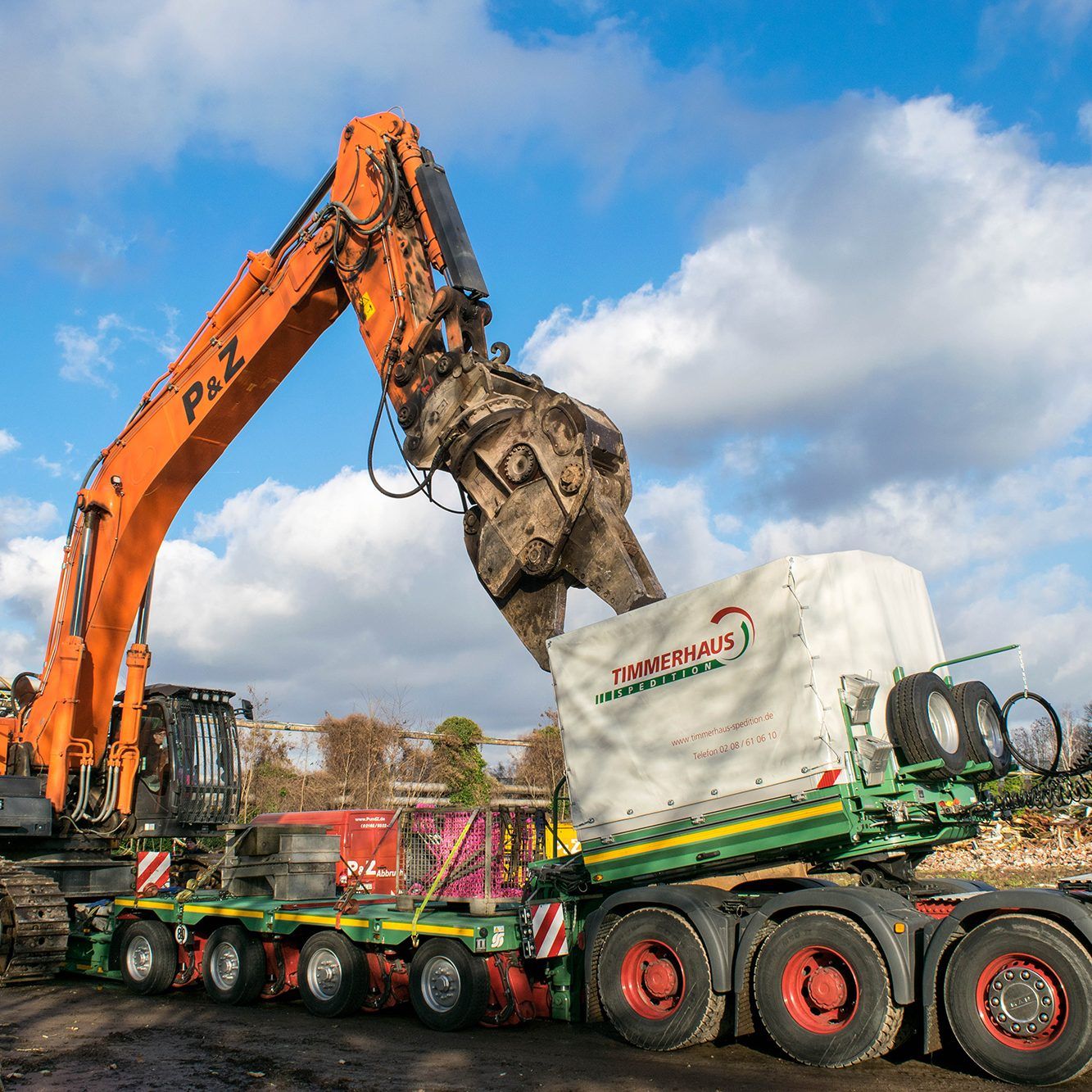 Excavator loading heavy equipment onto a trailer