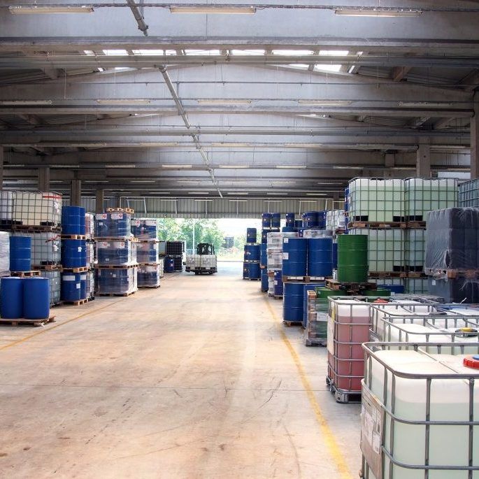 Warehouse interior with stacked drums and totes